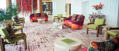 A spacious lobby with multiple seating areas, including sofas and chairs, and a patterned carpet.