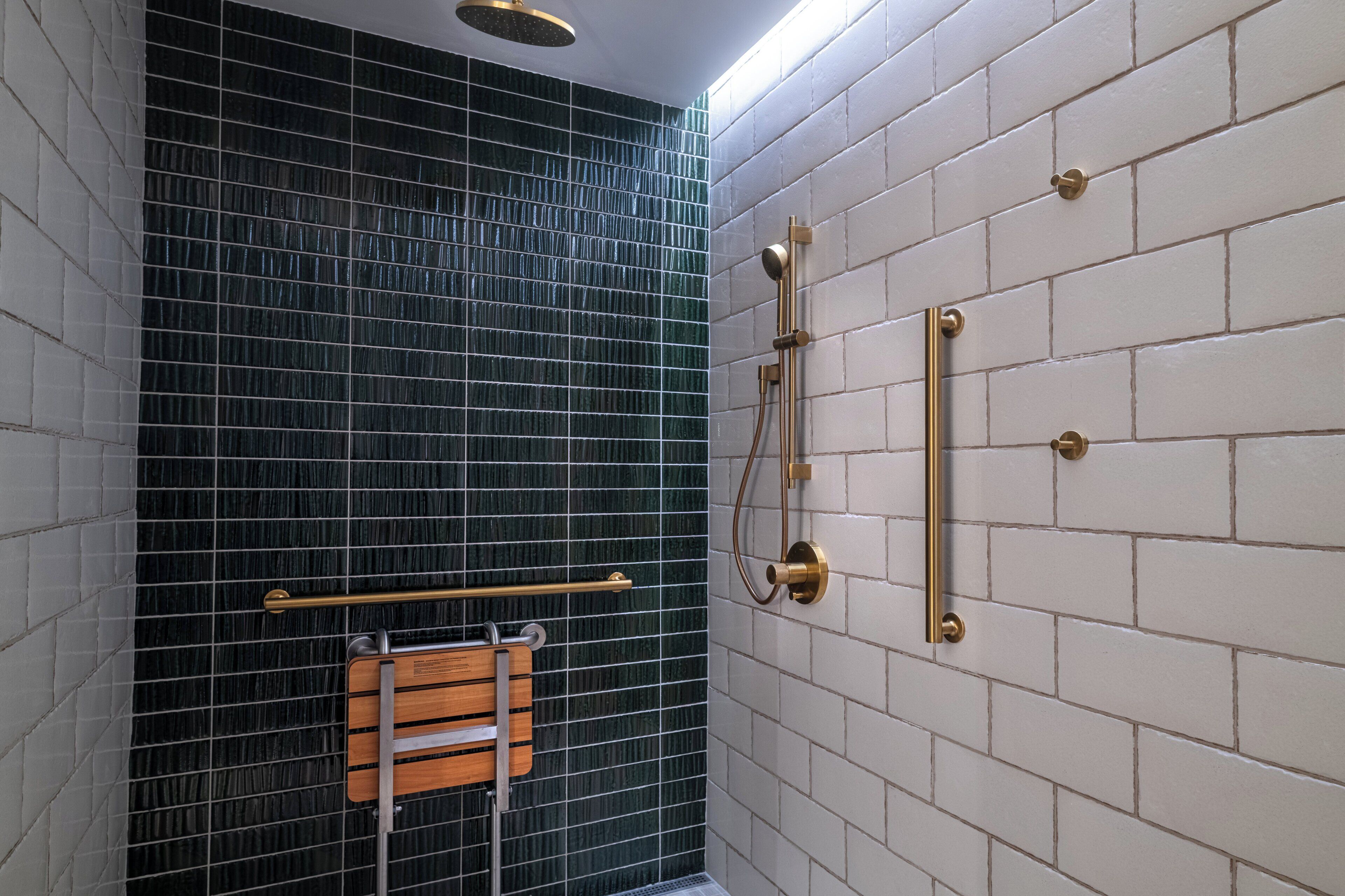 Un baño moderno con zona de ducha, paredes con azulejos y un banco de madera.