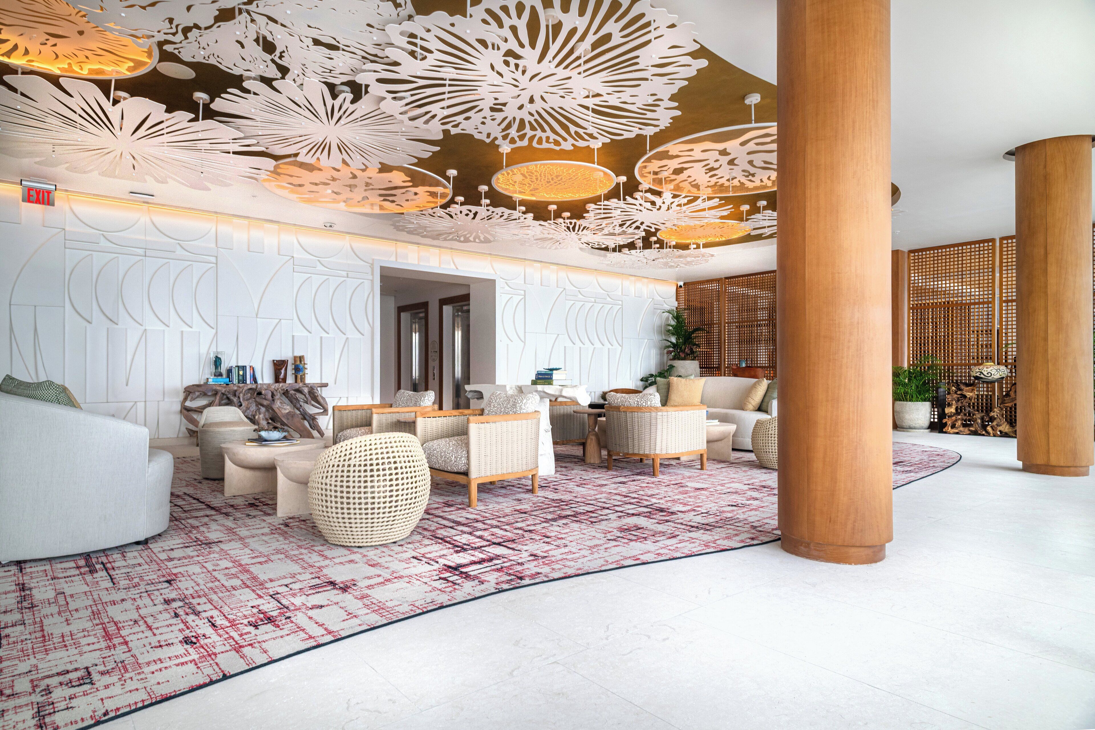 A spacious lobby with modern furniture, a patterned rug, and decorative ceiling panels.
