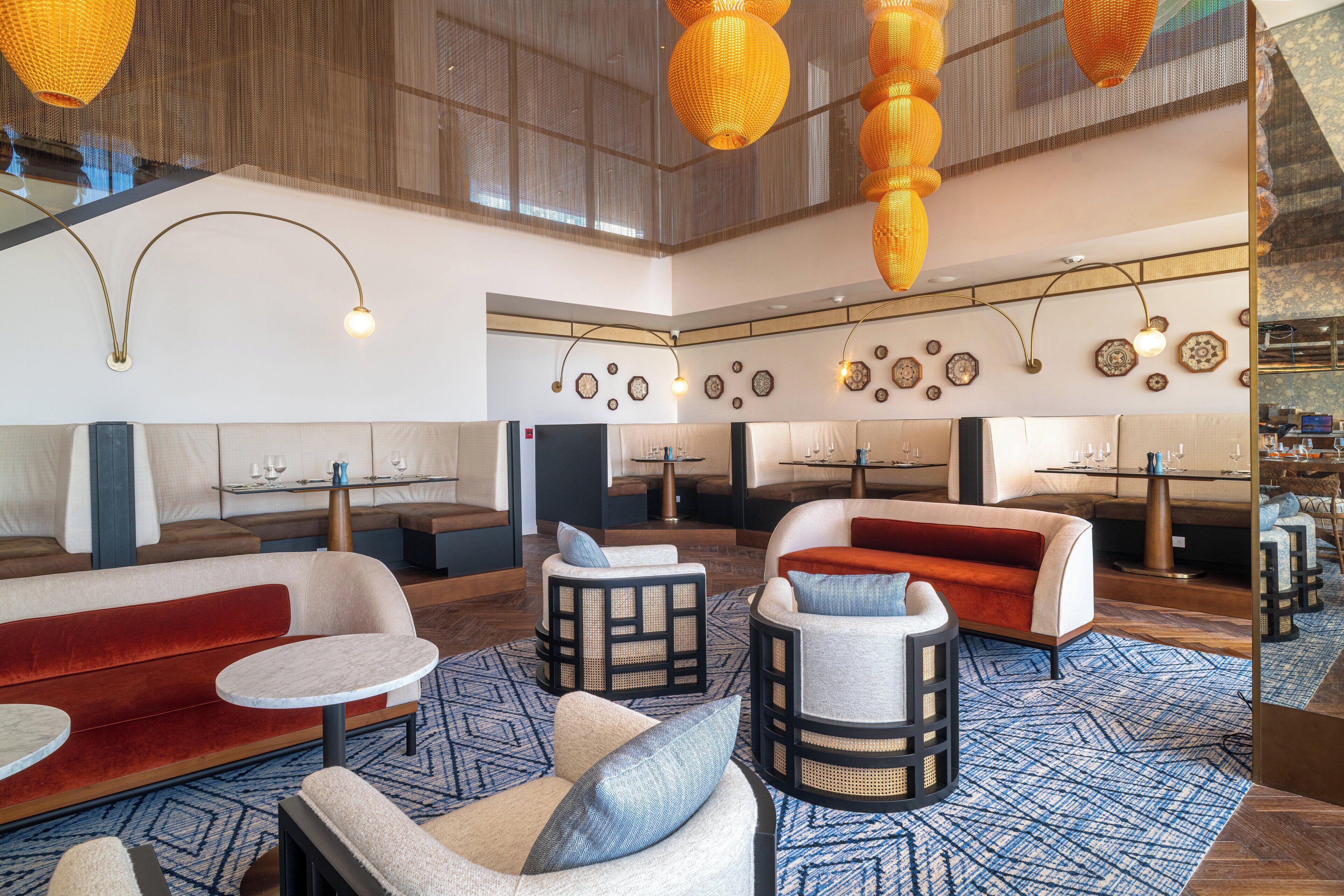 A spacious lounge area with multiple seating options, including sofas and chairs, arranged around tables.