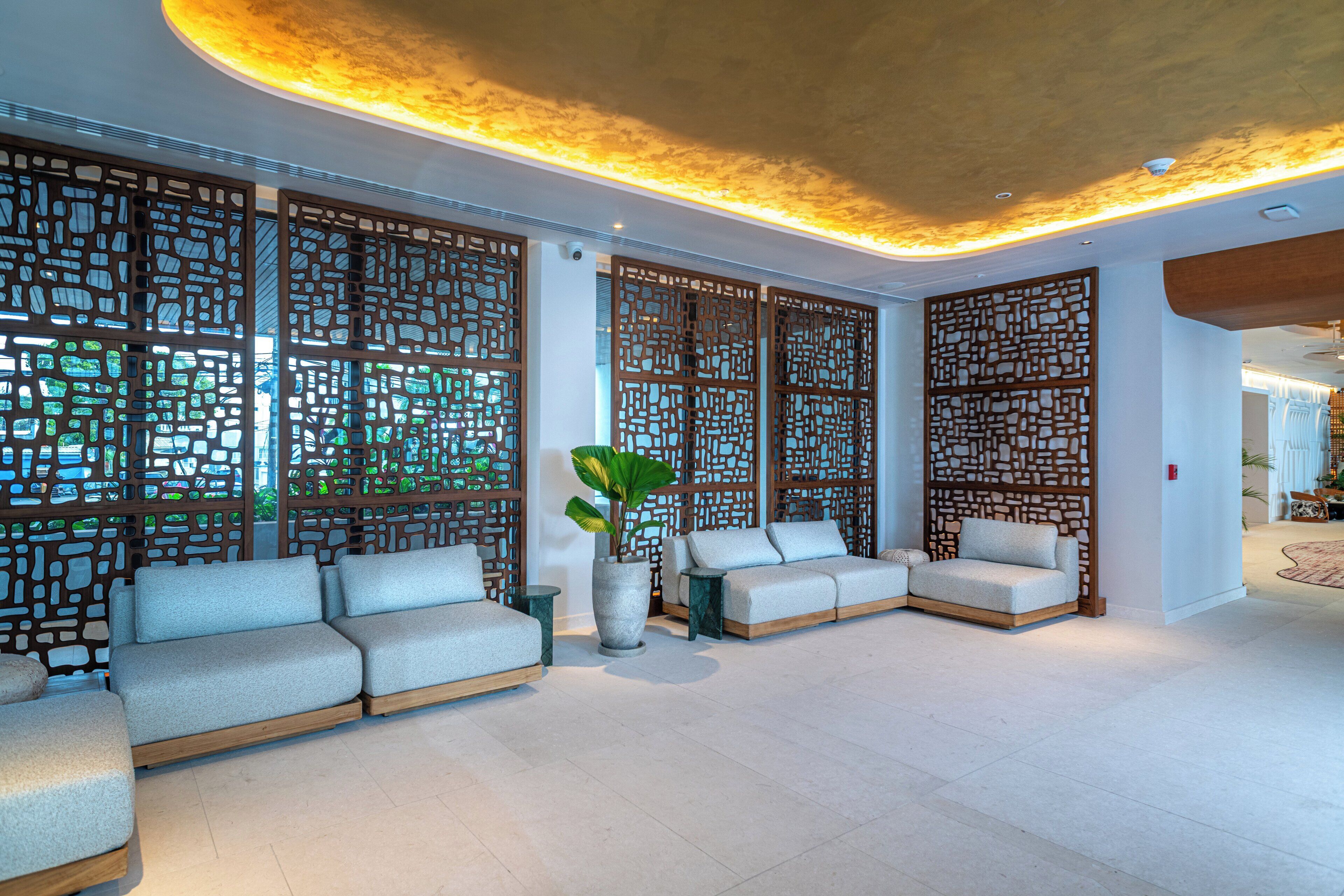 A modern lounge area with a sofa set, decorative screens, and a potted plant.