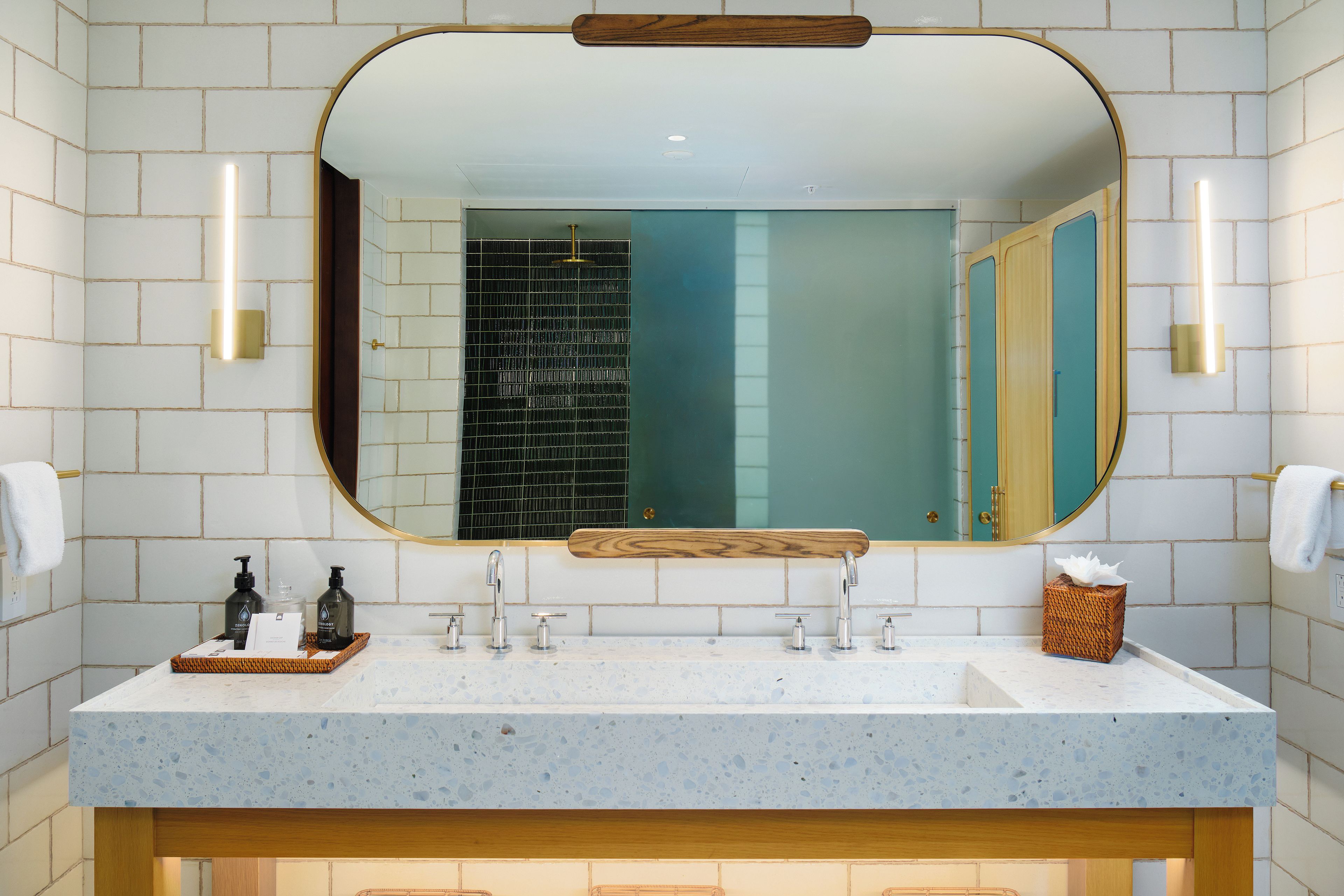 A bathroom with a large mirror, two sinks, and a towel rack.