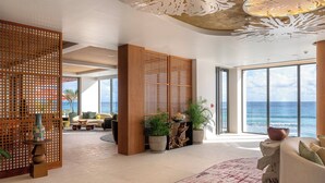 A spacious lobby with a large window offering a view of the ocean, wooden decor, and potted plants. - Hotel Indigo Bridgetown Barbados by IHG (Hastings)