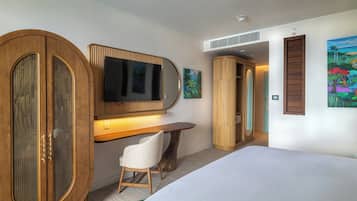 A hotel room with a bed, a desk with a chair, a television, and a wardrobe.