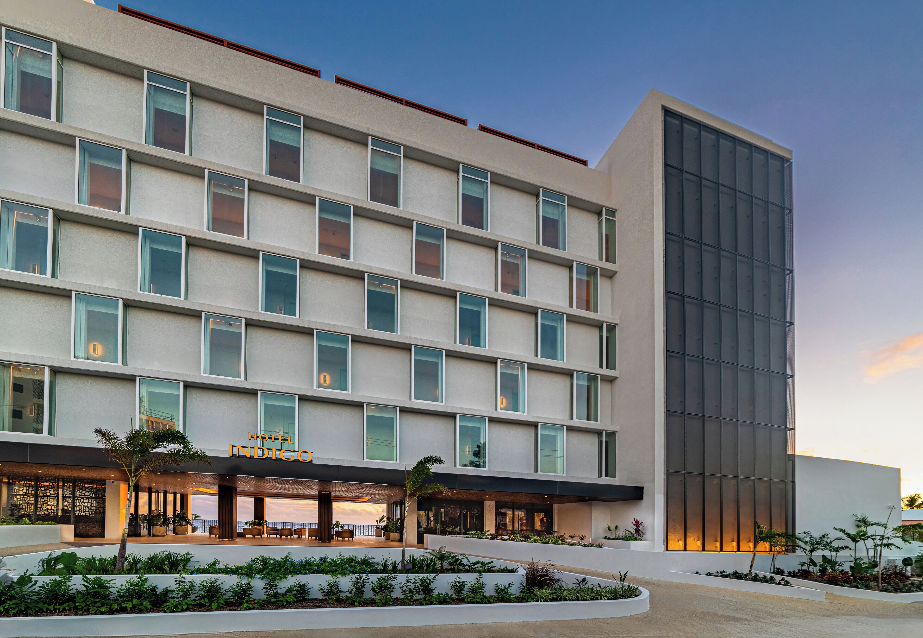 A modern hotel with a flat facade, large windows, and a landscaped entrance area.