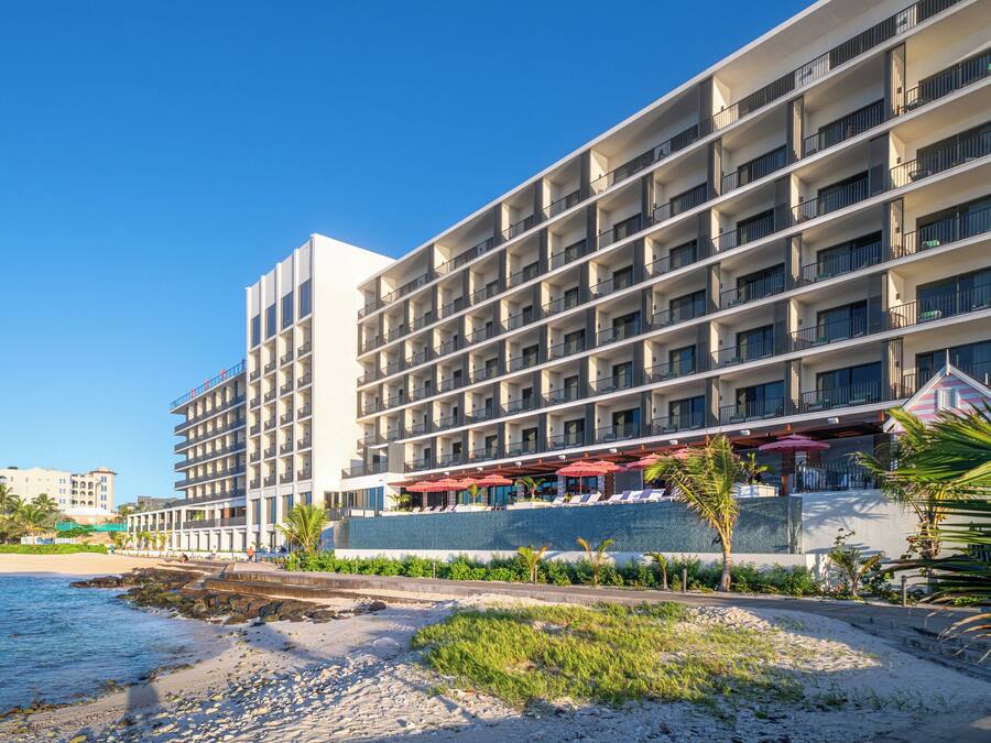 Um hotel com vários andares, varandas, área de piscina e vista para a praia.