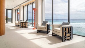 A spacious room with large windows offering ocean views, comfortable seating, and a modern design. - Hotel Indigo Bridgetown Barbados by IHG (Hastings)