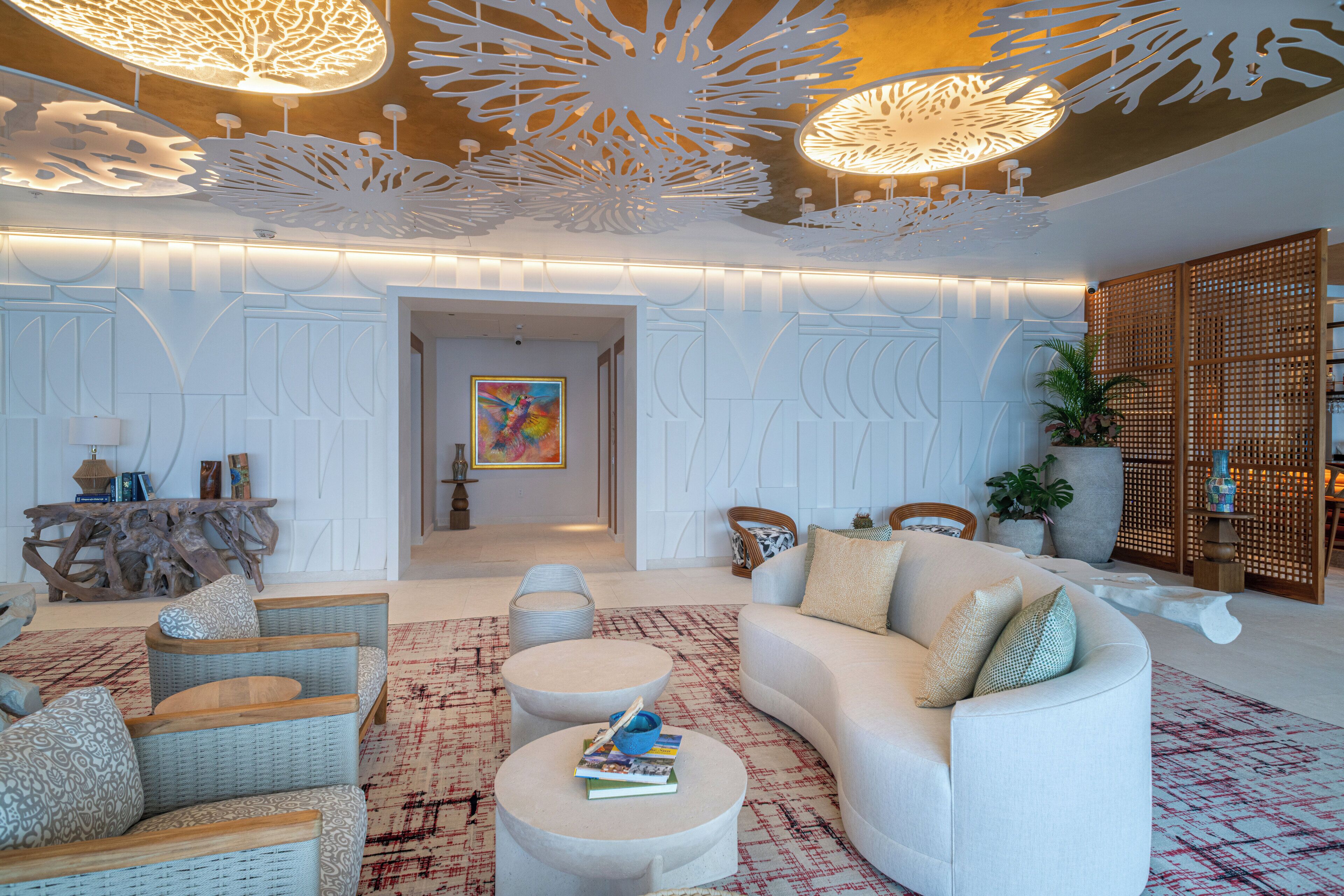 Una sala de estar moderna con un sofá blanco, dos mesas redondas de centro, sillas de mimbre y un techo decorativo.