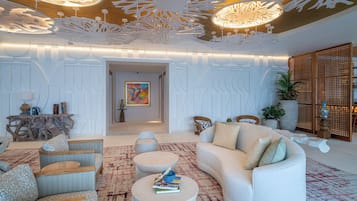 A modern living room with a white sofa, two round coffee tables, wicker chairs, and a decorative ceiling.