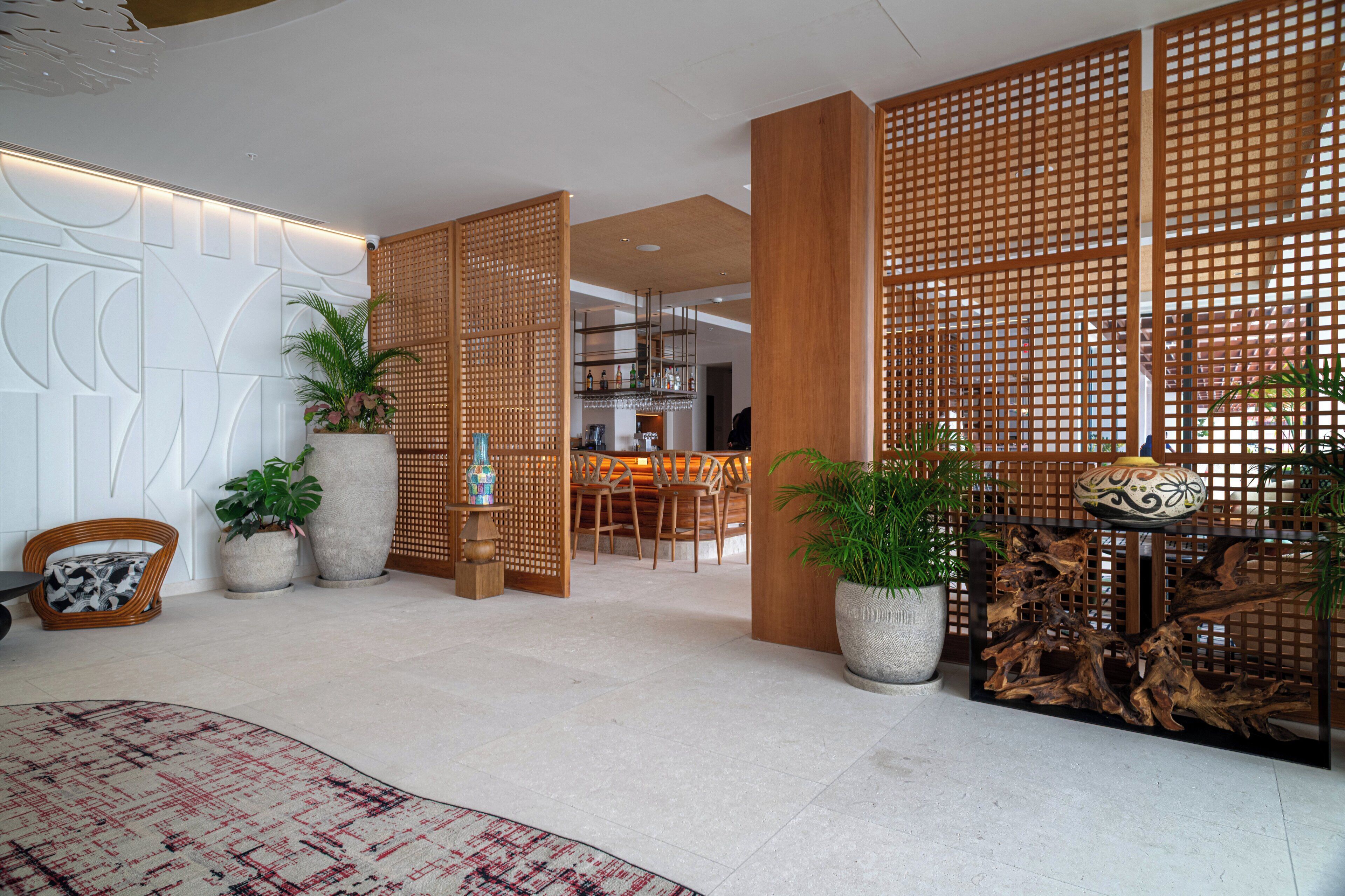 A modern interior with a bar area, wooden partitions, and potted plants.