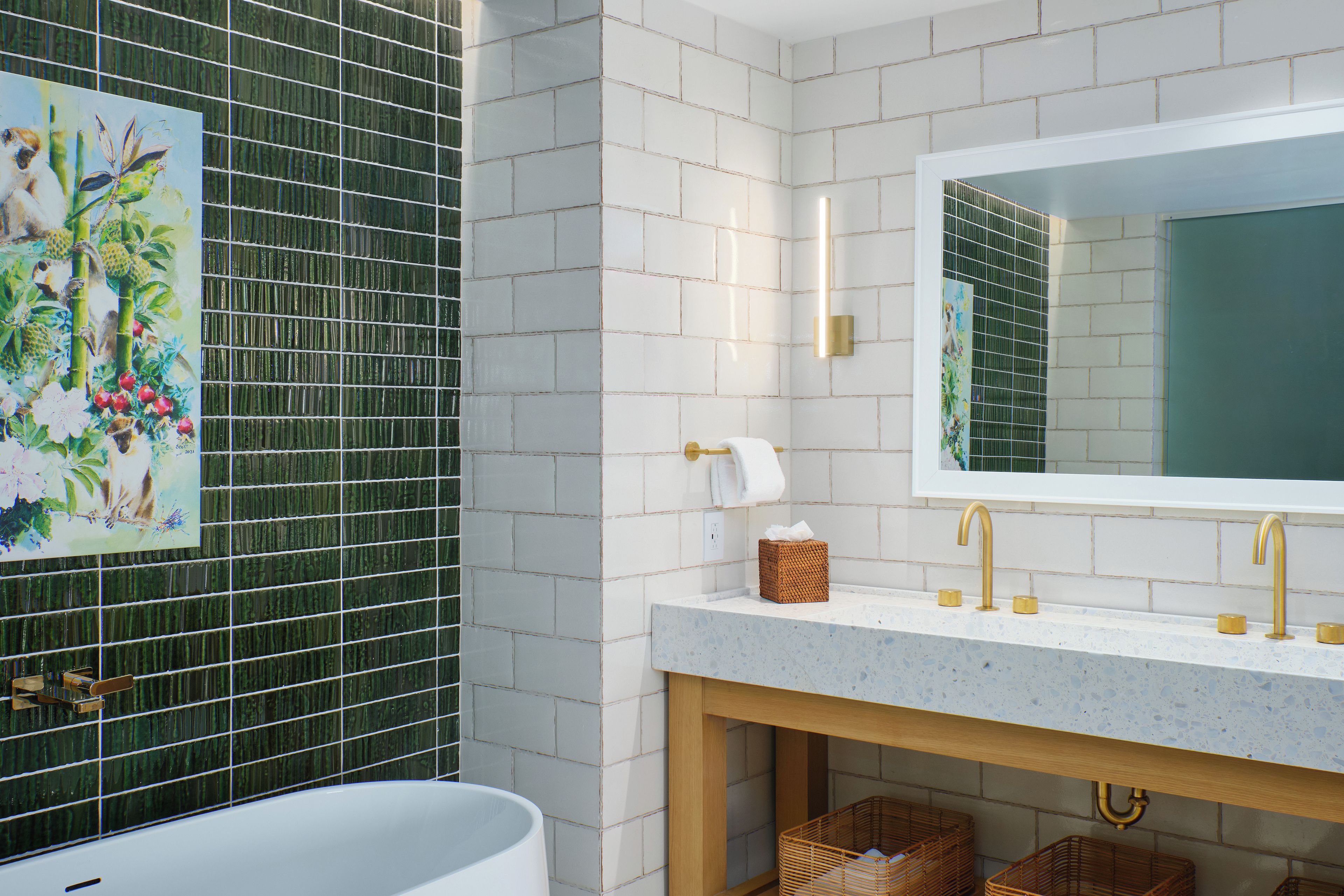 A bathroom with a white bathtub, a large mirror, and a green tiled wall.