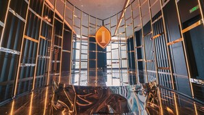 A modern interior with a reflective floor, vertical metal railings, and a central illuminated 'I' sign. - Intercontinental Changchun High Tech Zone by IHG (Changchun)