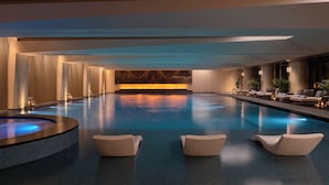 A modern indoor swimming pool with a hot tub, lounge chairs, and a marble wall. - Intercontinental Changchun High Tech Zone by IHG (Changchun)