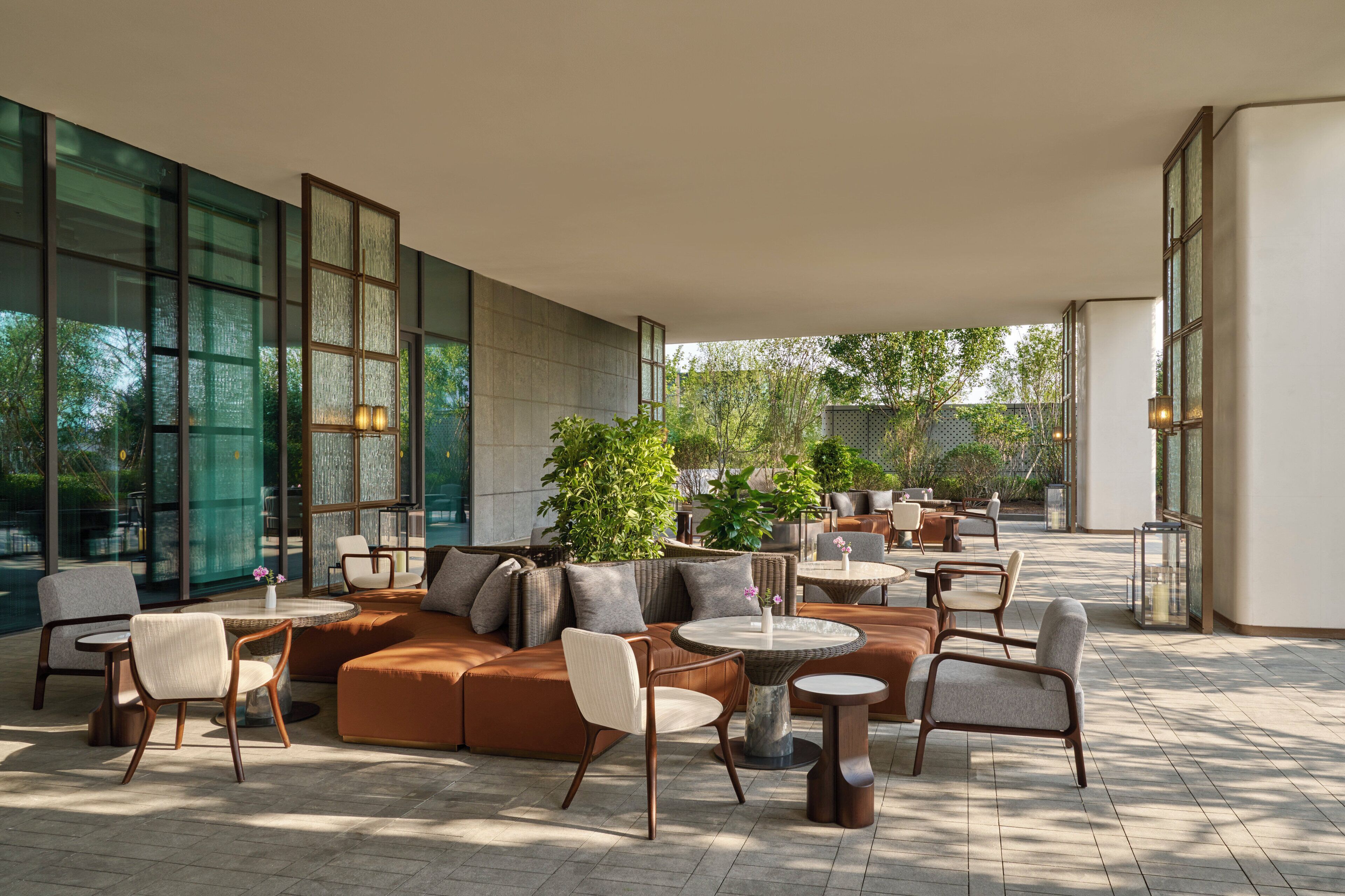 A spacious outdoor lounge area with a mix of seating options including sofas, chairs, and round tables.