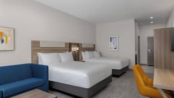 Een hotelkamer met een groot bed, twee nachtkastjes, een blauwe bank, een gele stoel en een houten bureau.