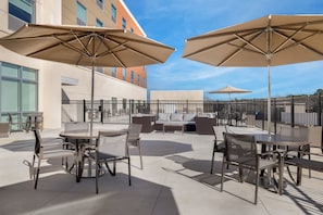 An outdoor patio with tables and chairs, large umbrellas, and a sofa set.