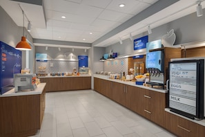 A modern breakfast area with a self-serve station, a digital menu display, and a refrigerator with yogurt, eggs, and milk. - Holiday Inn Express And Suites Huntsville Northeast by IHG (Huntsville)