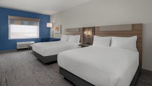 A hotel room with two beds, a window with blinds, a bedside table, and a wall-mounted lamp. - Holiday Inn Express And Suites Huntsville Northeast by IHG (Huntsville)