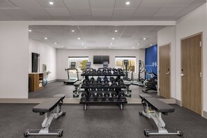Un gimnasio con equipamiento de levantamiento de pesas, cintas de correr y máquinas de ejercicio.