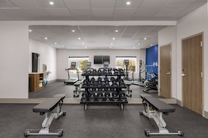 Un gimnasio con equipamiento de levantamiento de pesas, cintas de correr y máquinas de ejercicio.