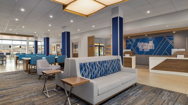 A modern hotel lobby with a reception desk, seating area, and a food kiosk. - Holiday Inn Express And Suites Huntsville Northeast by IHG (Huntsville)