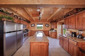 A kitchen with wooden cabinets, stainless steel appliances, granite countertops, and a central island. - Family-Friendly 12BR Lodge w/Games & Mtn. Views (Sevierville)
