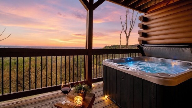 Un bain à remous sur une terrasse en bois, avec vue sur le coucher de soleil.