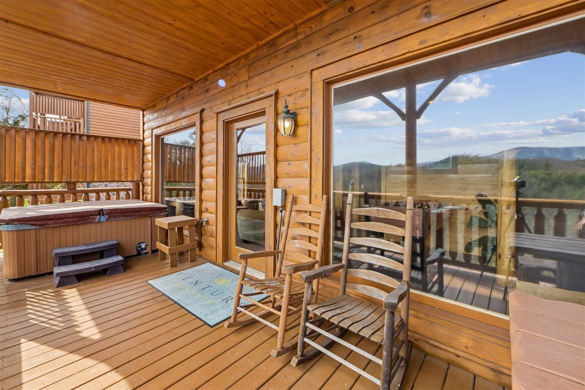 Eine Holzterrasse mit einem Whirlpool, Holzstühlen und Blick auf die Berge.