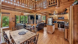 Ein Holzblockhaus im Inneren mit Essbereich, Küche, Kamin und Schornstein.