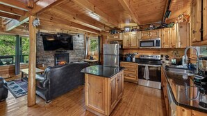 Ein Holzhaus-Interieur mit Kamin aus Stein, einer Küche mit modernen Geräten und einer Sitzecke.
