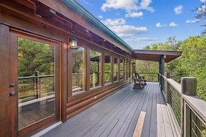 A wooden deck with large windows, a pergola, and outdoor seating.