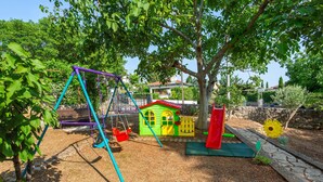 Ein Spielplatz mit Schaukeln, einem kleinen Häuschen und einer Rutsche.