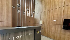 Una reception dal design moderno, caratterizzata da un pannello parete in legno verticale e una segnaletica con la scritta 'RECEPTION'.