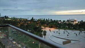 Vista di una città costiera con un parco, un corso d'acqua e un ponte all'orizzonte.