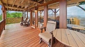 A wooden deck with outdoor seating, large windows, and a view of the outdoors. - Luxury Cabin w/ Games, Views & Hot Tub (Sevierville)