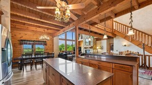 A spacious kitchen with wooden cabinets, a granite countertop, and a central island. - Grand Smoky Mountain Cabin w/ Views & Hot Tub (Sevierville)