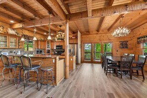 A wooden cabin interior with a kitchen, dining area, and bar seating.