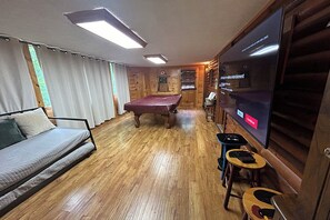 A cozy room with a pool table, a sofa, and a television.