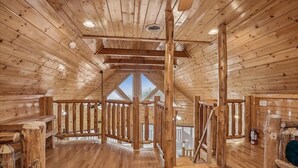 A wooden interior with a high ceiling, wooden beams, and a staircase leading to an upper level. - Luxe Cabin w/ Breathtaking Smoky Mountain Views (Sevierville)