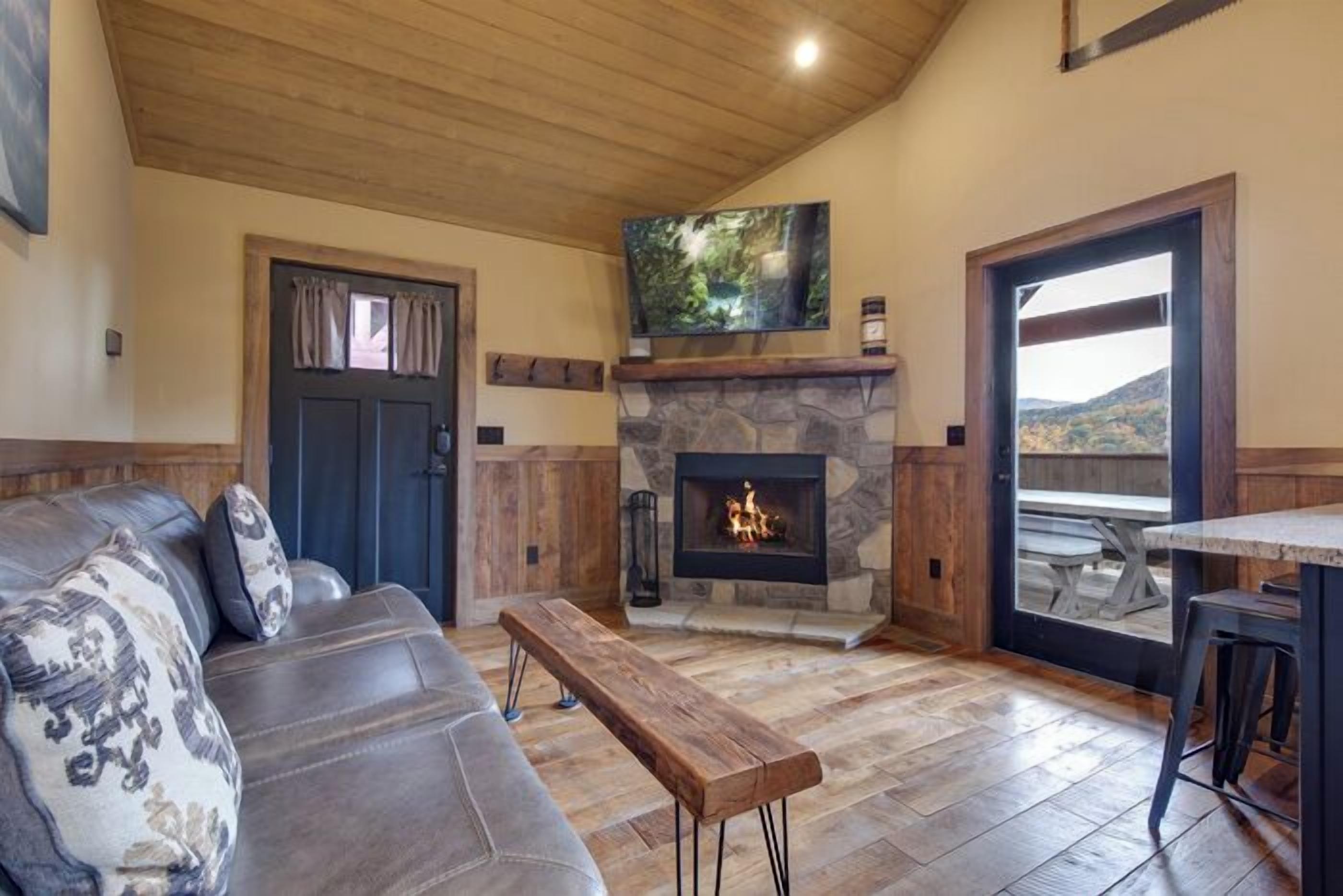 A cozy living room with a stone fireplace, a comfortable sofa, and a wooden bench.