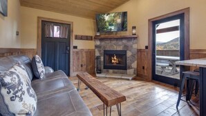 Un salon chaleureux avec une cheminée en pierre, un canapé confortable et un banc en bois.