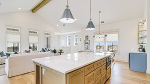 A spacious kitchen with a large island, wooden cabinets, and pendant lighting.