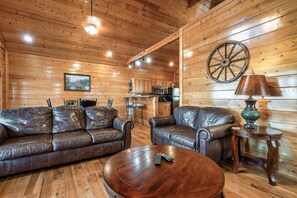 Un intérieur en bois avec des canapés en cuir, une table basse ronde, une lampe et un volant fixé au mur.