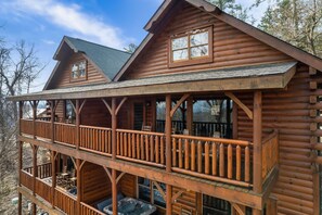 A log cabin with a balcony and a hot tub.