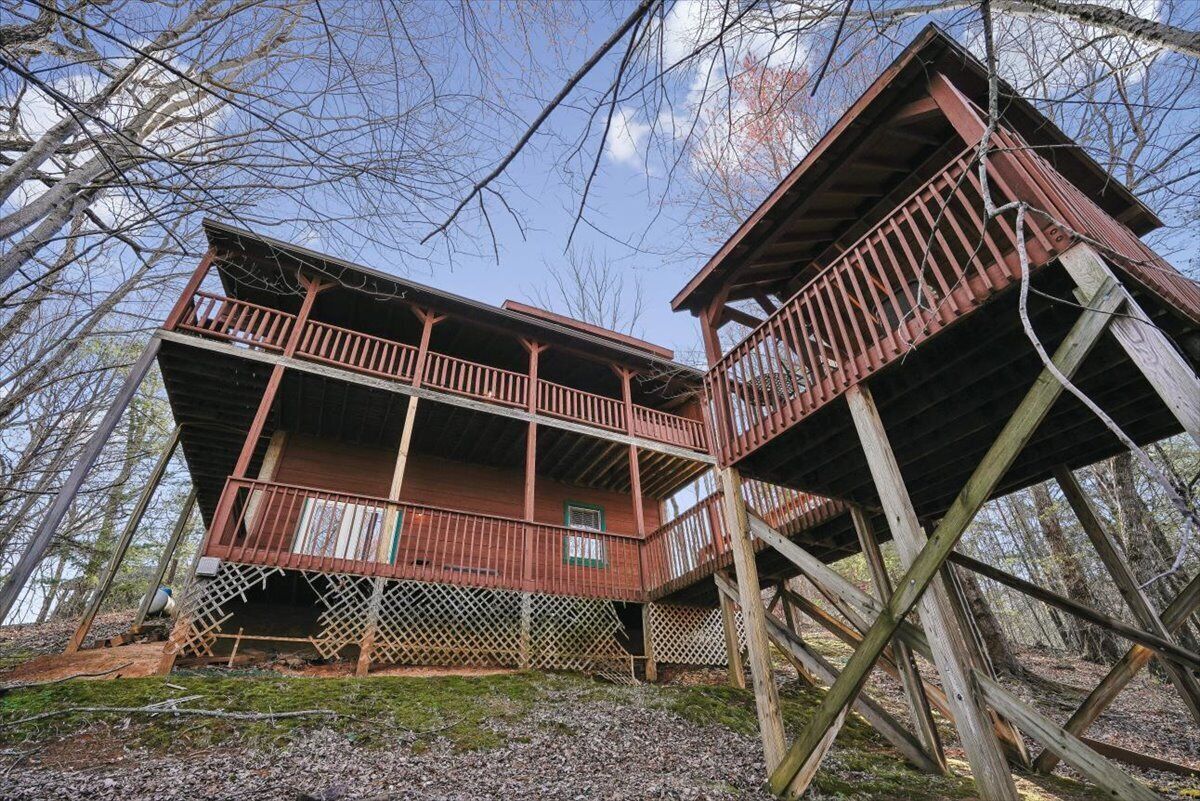 A wooden cabin with a balcony, surrounded by trees.