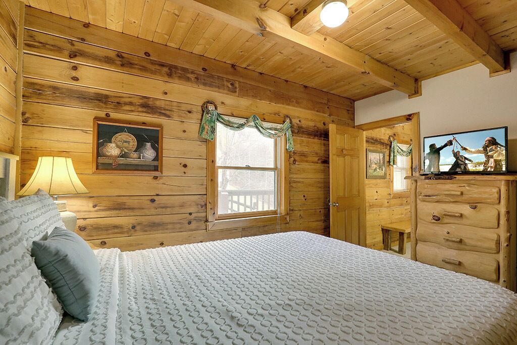 Un dormitorio de cabaña de madera con cama, cómoda y un cuadro en la pared.
