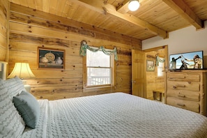 A wooden cabin bedroom with a bed, dresser, and a painting on the wall.