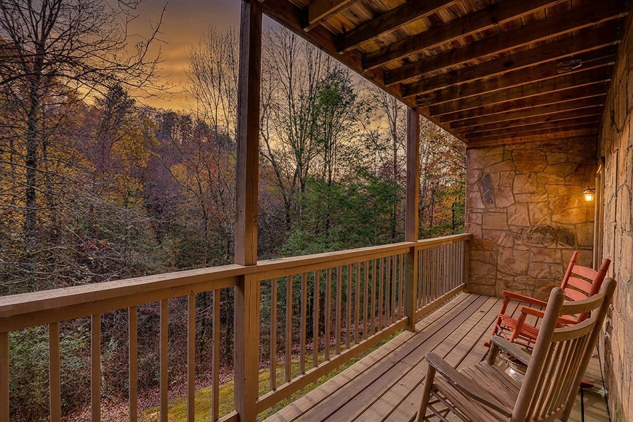 A wooden deck with a stone wall and a view of a forest.