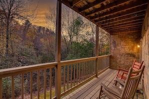 Une terrasse en bois avec un mur en pierre et une vue sur une forêt.