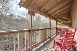 A covered wooden deck with a sign reading "The Ponderosa," wooden chairs, and a view of a forested area.